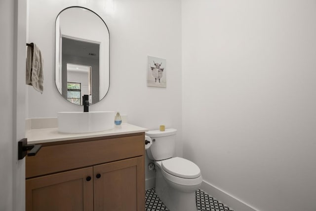 half bathroom with baseboards, toilet, and vanity