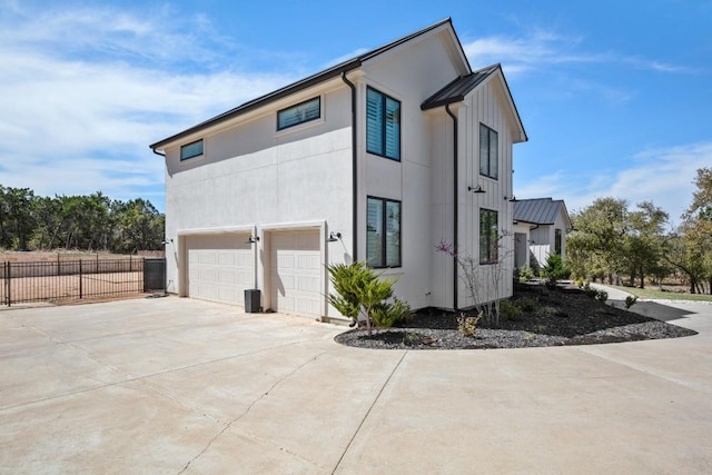 view of property exterior with stucco siding, driveway, an attached garage, and fence