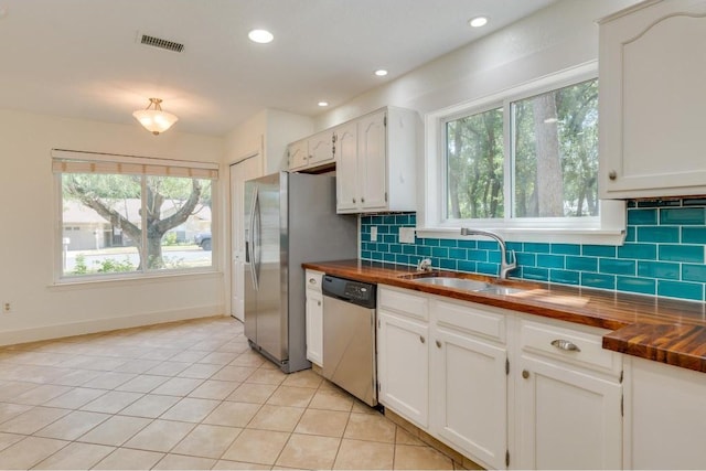 kitchen with a sink, stainless steel appliances, visible vents, and wood counters