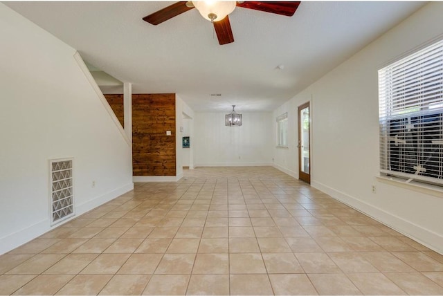 unfurnished living room featuring light tile patterned floors, ceiling fan with notable chandelier, visible vents, and baseboards