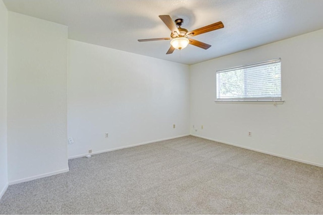 empty room featuring light colored carpet, a textured ceiling, baseboards, and ceiling fan