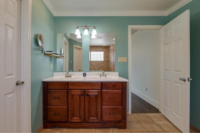 bathroom with a sink, tiled shower, ornamental molding, and double vanity