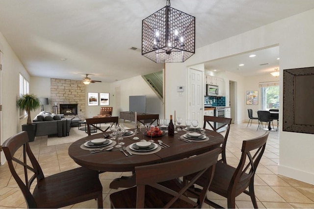 dining room with light tile patterned flooring, plenty of natural light, and a stone fireplace