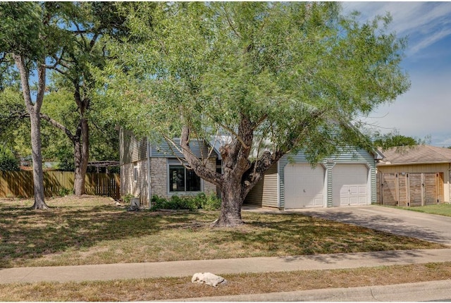 view of front of home with stone siding, concrete driveway, a front yard, and fence