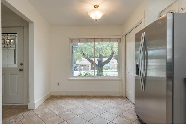 kitchen with light tile patterned floors, baseboards, and stainless steel fridge with ice dispenser