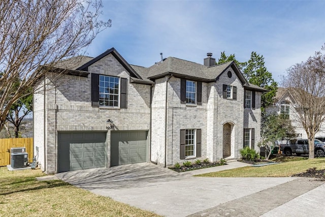 french provincial home with fence, a front lawn, concrete driveway, a garage, and brick siding