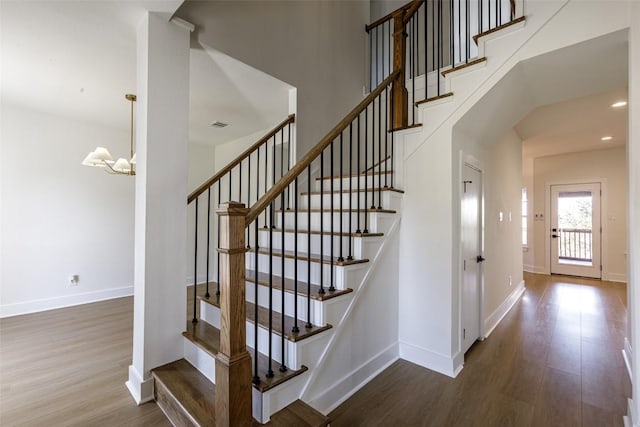 staircase with a towering ceiling, recessed lighting, baseboards, and wood finished floors