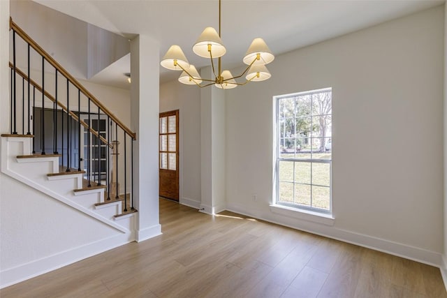 interior space with stairs, an inviting chandelier, wood finished floors, and baseboards