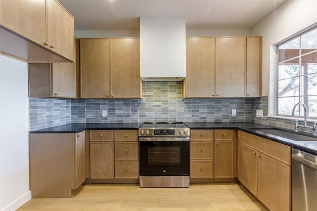 kitchen with a sink, tasteful backsplash, light wood-style floors, and appliances with stainless steel finishes