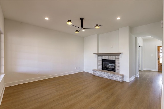 unfurnished living room with a fireplace, recessed lighting, wood finished floors, and baseboards