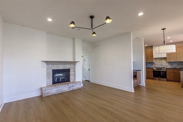 unfurnished living room with visible vents, baseboards, recessed lighting, light wood-style flooring, and a fireplace