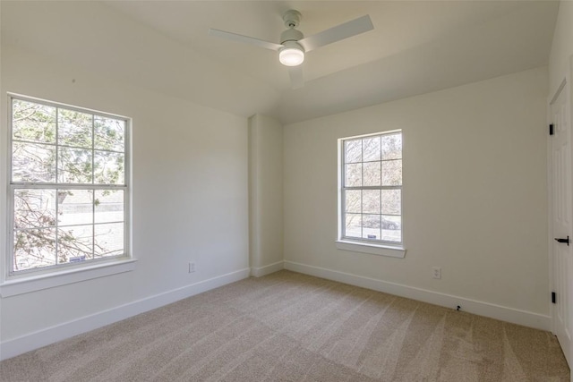 spare room featuring ceiling fan, vaulted ceiling, baseboards, and light carpet