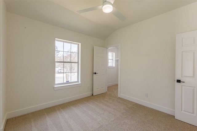 interior space featuring vaulted ceiling, light colored carpet, baseboards, and ceiling fan