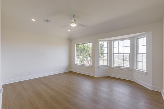 empty room with ceiling fan, visible vents, baseboards, and wood finished floors