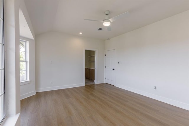 empty room with light wood finished floors, visible vents, baseboards, vaulted ceiling, and a ceiling fan