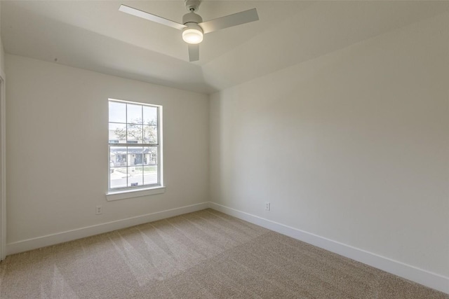 spare room featuring light colored carpet, a ceiling fan, and baseboards