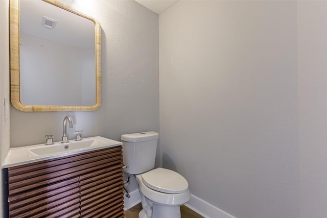 half bathroom featuring visible vents, baseboards, toilet, and vanity