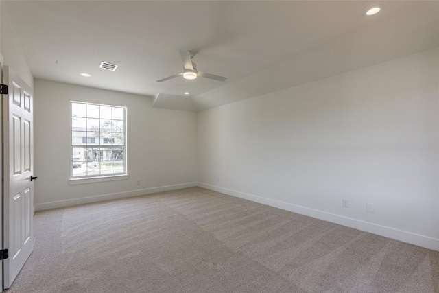 unfurnished room with visible vents, light colored carpet, baseboards, and ceiling fan