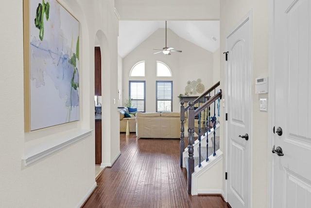 foyer entrance with dark wood-style floors, a ceiling fan, baseboards, high vaulted ceiling, and stairs