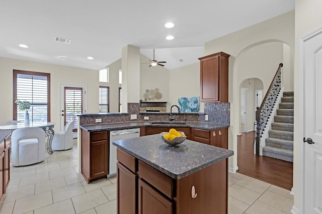 kitchen featuring visible vents, a peninsula, arched walkways, a sink, and stainless steel dishwasher