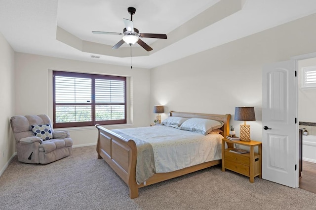 bedroom with visible vents, baseboards, a tray ceiling, ceiling fan, and light colored carpet