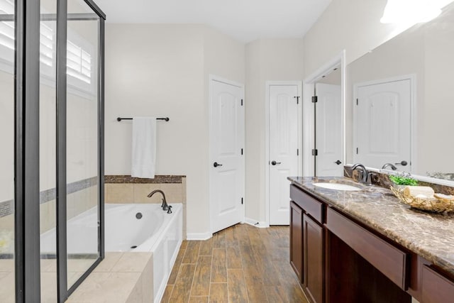 bathroom with vanity, a garden tub, wood finished floors, and a stall shower