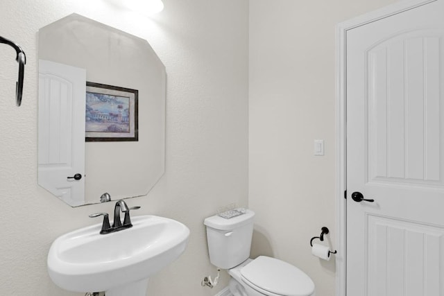 bathroom featuring toilet, baseboards, and a sink