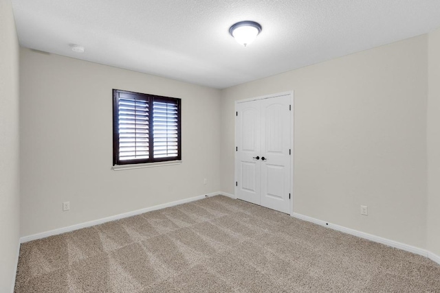 empty room featuring baseboards, a textured ceiling, and carpet flooring