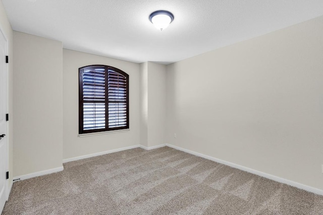 spare room featuring a textured ceiling, baseboards, and carpet floors