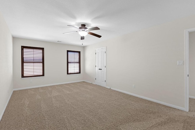 unfurnished room featuring baseboards, light colored carpet, and a ceiling fan