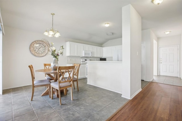 dining room featuring light tile patterned floors, a notable chandelier, baseboards, and vaulted ceiling