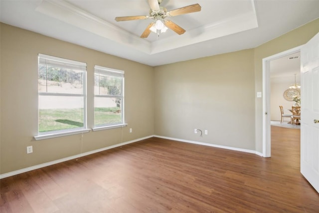 spare room with baseboards, a raised ceiling, and wood finished floors