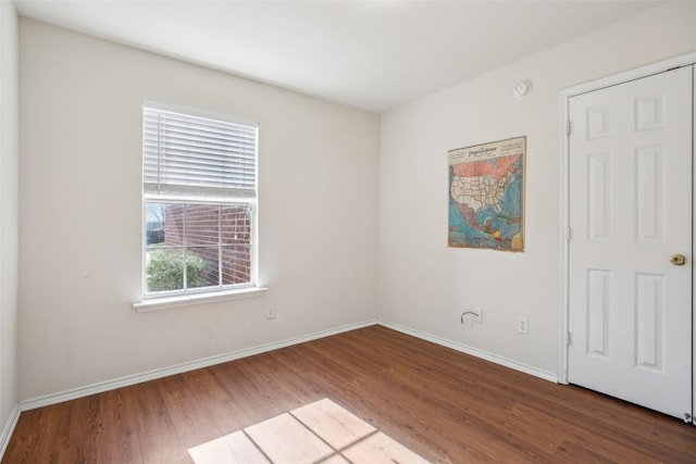 spare room with baseboards and wood finished floors