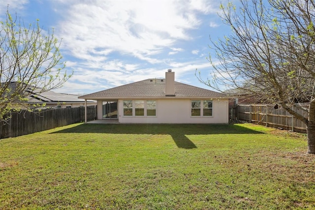 rear view of property with a yard, a chimney, a fenced backyard, and roof with shingles