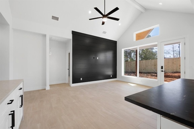 interior space featuring light wood finished floors, visible vents, beam ceiling, high vaulted ceiling, and a ceiling fan