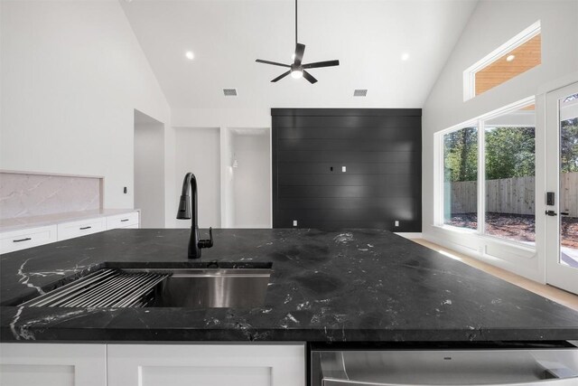 113 Eaglenest Ct, Smithville, TX 78957 - kitchen with high vaulted ceiling, dark stone counters, white cabinetry, stainless steel dishwasher, and ceiling fan
