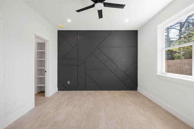 spare room with light wood-style flooring, recessed lighting, baseboards, ceiling fan, and an accent wall