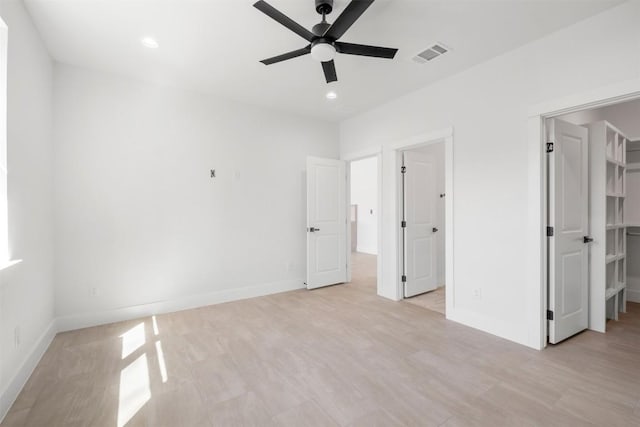 unfurnished bedroom with visible vents, a walk in closet, baseboards, light wood-type flooring, and recessed lighting