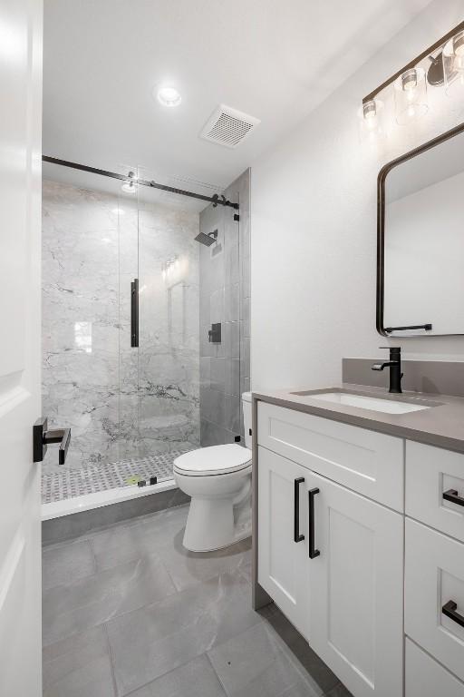 full bathroom with a marble finish shower, visible vents, toilet, marble finish floor, and vanity