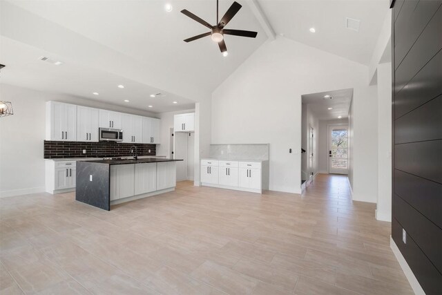 113 Eaglenest Ct, Smithville, TX 78957 - kitchen featuring stainless steel microwave, dark countertops, a ceiling fan, tasteful backsplash, and beam ceiling