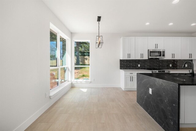 113 Eaglenest Ct, Smithville, TX 78957 - kitchen with stainless steel microwave, white cabinets, decorative backsplash, recessed lighting, and decorative light fixtures