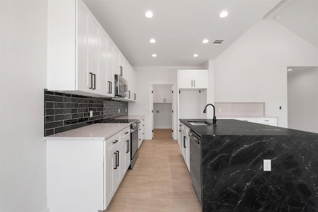 kitchen featuring dark stone countertops, visible vents, a sink, stainless steel appliances, and tasteful backsplash