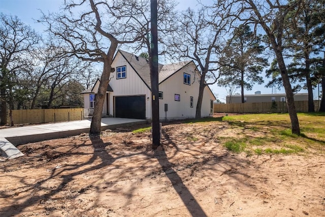 view of side of home featuring concrete driveway, an attached garage, and fence