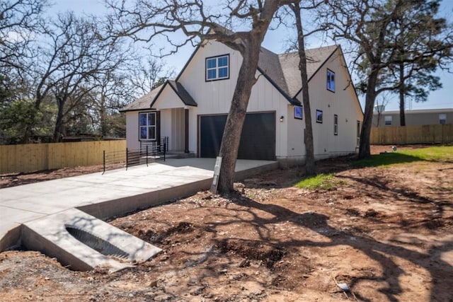 view of front of property with board and batten siding, concrete driveway, an attached garage, and fence