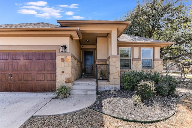 view of exterior entry featuring stucco siding, stone siding, a garage, and roof with shingles