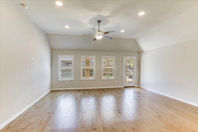 spare room featuring wood finished floors, a ceiling fan, baseboards, and lofted ceiling