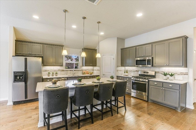 kitchen featuring hanging light fixtures, light wood finished floors, appliances with stainless steel finishes, and a center island