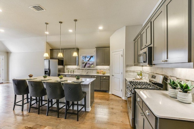 kitchen featuring tasteful backsplash, visible vents, a kitchen island, a breakfast bar area, and stainless steel appliances