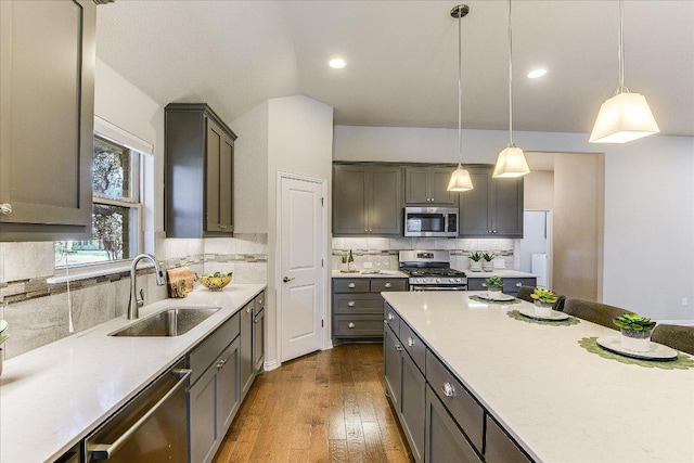 kitchen with pendant lighting, a sink, tasteful backsplash, stainless steel appliances, and dark wood-style flooring