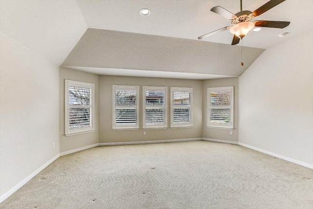 carpeted empty room featuring a ceiling fan, lofted ceiling, and a healthy amount of sunlight